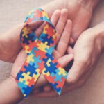 Hands holding puzzle ribbon for autism awareness