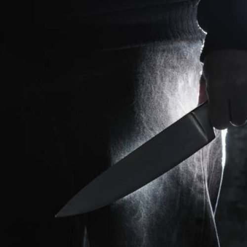 Dark photo of a man holding a big knife, crime concept.