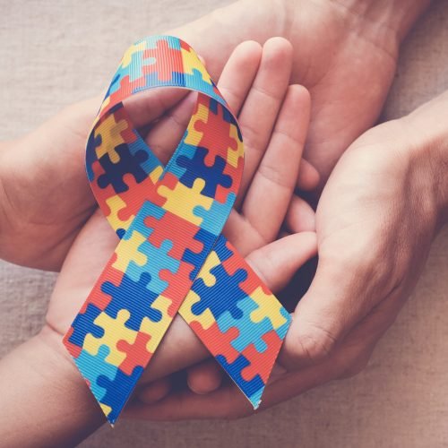 Hands holding puzzle ribbon for autism awareness