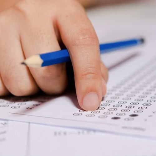 Students hand holding pencil writing selected choice on answer sheets and Mathematics question sheets. students testing doing examination. school exam